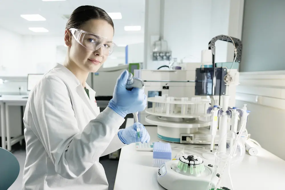 Una científica está trabajando en un laboratorio, con bata y gafas de seguridad.
