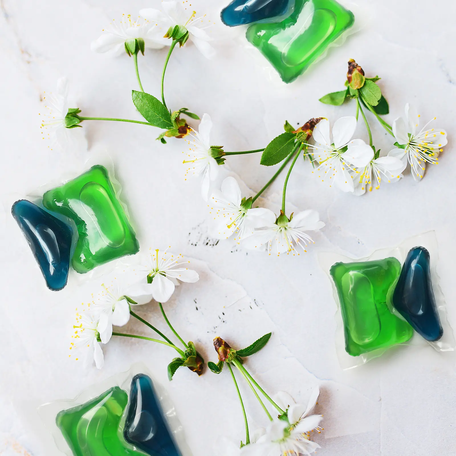 Dos cápsulas verdes y azules de Persil con flores de cerezo alrededor.
