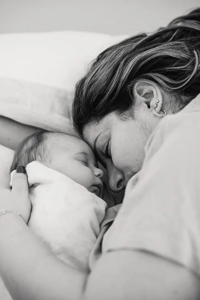 Foto en blanco y negro de un abrazo entre la cuidadora primaria y el bebé.