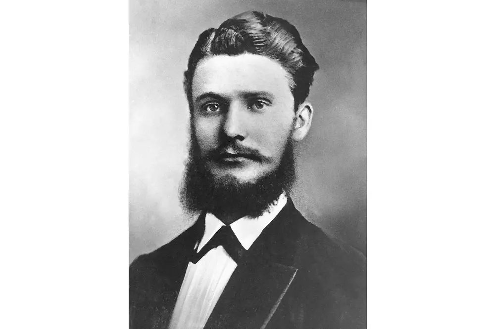 Retrato en blanco y negro de Fritz Henkel con atuendo formal, incluyendo saco oscuro y camisa de cuello alto.