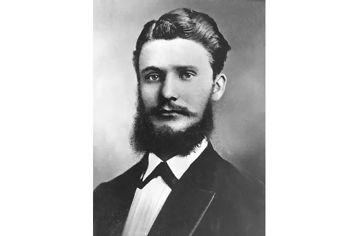 Retrato en blanco y negro de Fritz Henkel con atuendo formal, incluyendo saco oscuro y camisa de cuello alto.