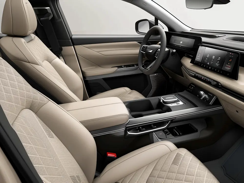 Interior de automóvil con asientos beige acolchados, tablero con pantallas digitales panorámicas y consola central con controles táctiles y detalles metálicos.